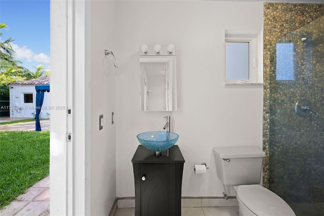 bathroom featuring vanity, tiled shower, tile patterned floors, and toilet