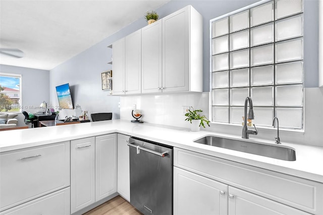 kitchen with sink, light hardwood / wood-style flooring, white cabinetry, stainless steel dishwasher, and kitchen peninsula