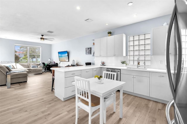 kitchen with sink, light hardwood / wood-style flooring, dishwasher, fridge, and kitchen peninsula