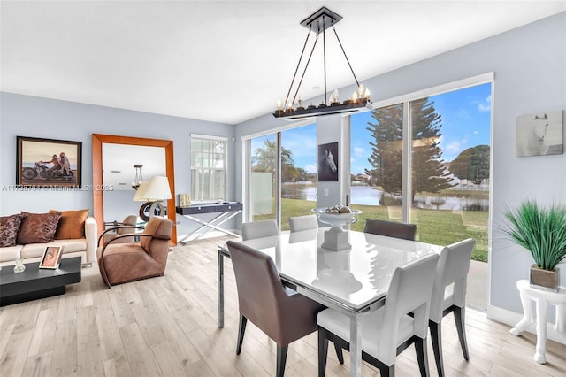 dining space featuring a water view, light hardwood / wood-style floors, and a notable chandelier