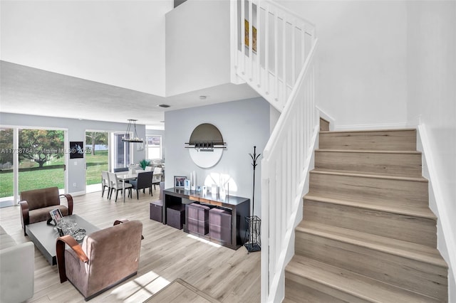 stairway featuring hardwood / wood-style flooring, a towering ceiling, and a chandelier