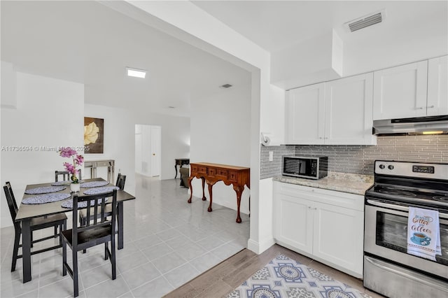 kitchen with electric stove, backsplash, light stone counters, light hardwood / wood-style floors, and white cabinets