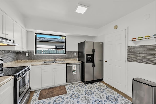 kitchen with sink, white cabinetry, appliances with stainless steel finishes, light stone countertops, and backsplash