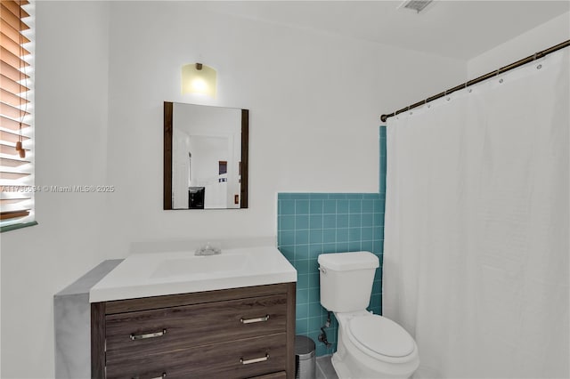 bathroom with vanity, toilet, and tile walls