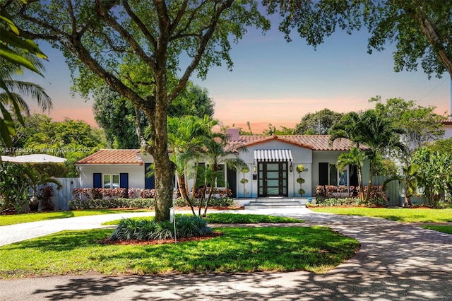 339 NE 100th St, Miami Shores, FL 33138 - mediterranean / spanish-style house featuring a tiled roof, curved driveway, stucco siding, and french doors