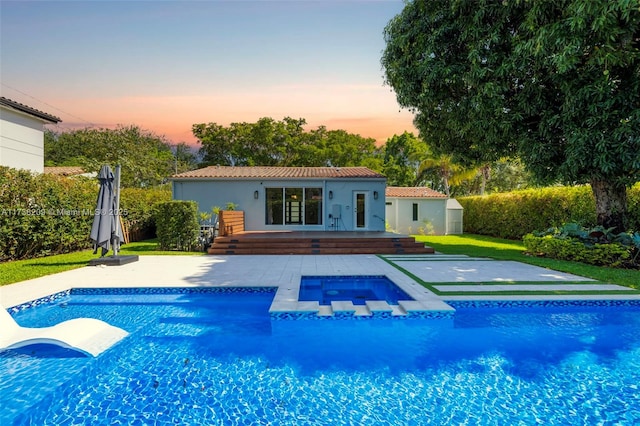 339 NE 100th St, Miami Shores, FL 33138 - pool at dusk with an in-ground hot tub, an outdoor pool, an outdoor structure, and a patio area