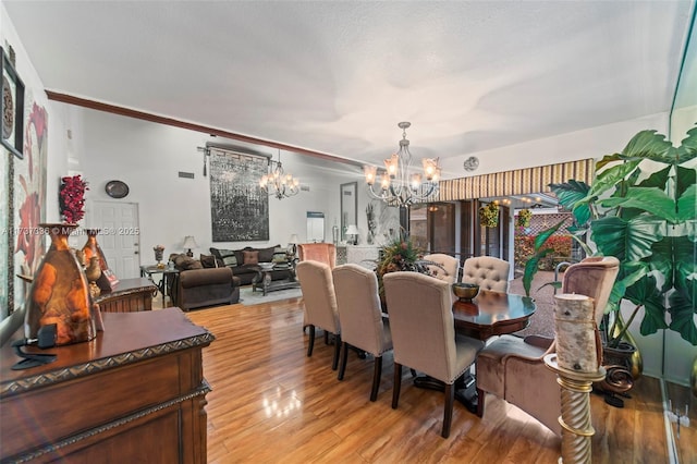 dining room featuring a notable chandelier, light hardwood / wood-style flooring, and a textured ceiling