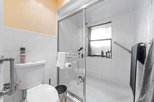 bathroom with tile walls, a shower with shower door, and toilet