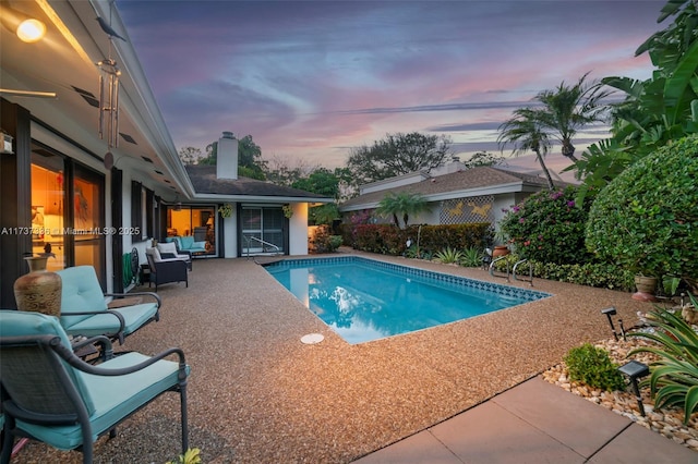 pool at dusk with a patio area