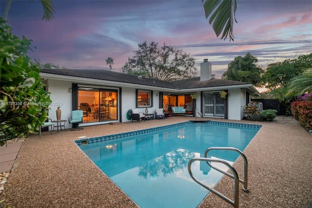 pool at dusk with a patio area