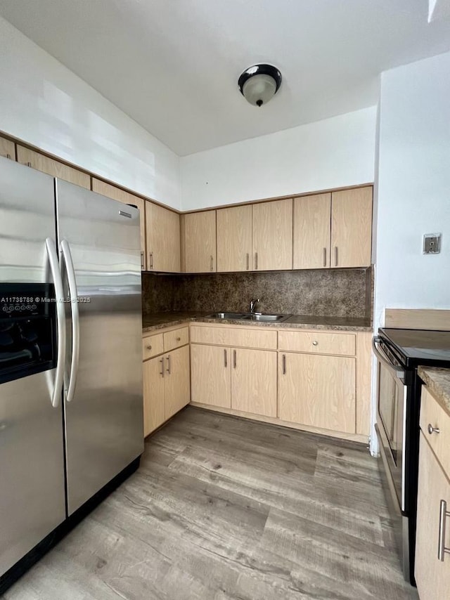 kitchen with light brown cabinetry, sink, light wood-type flooring, appliances with stainless steel finishes, and backsplash