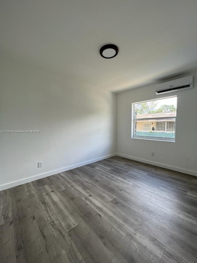 empty room featuring dark wood-type flooring and a wall mounted AC