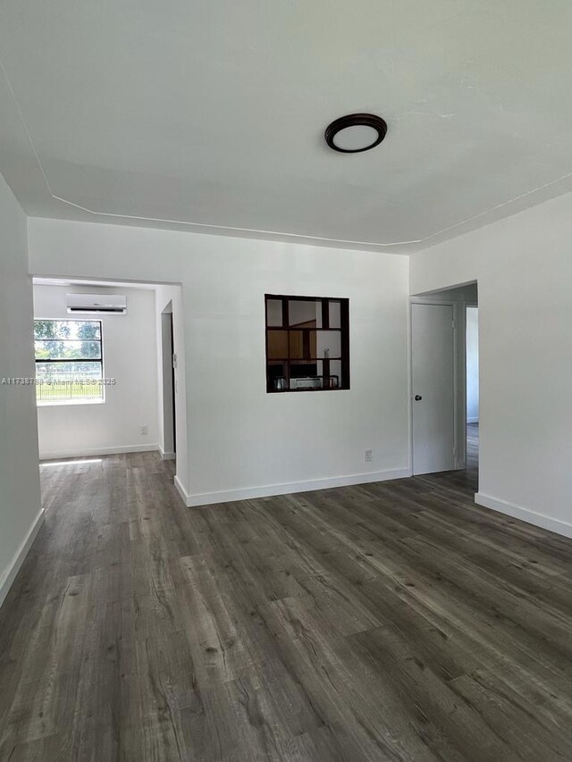 empty room with a wall unit AC and dark hardwood / wood-style flooring