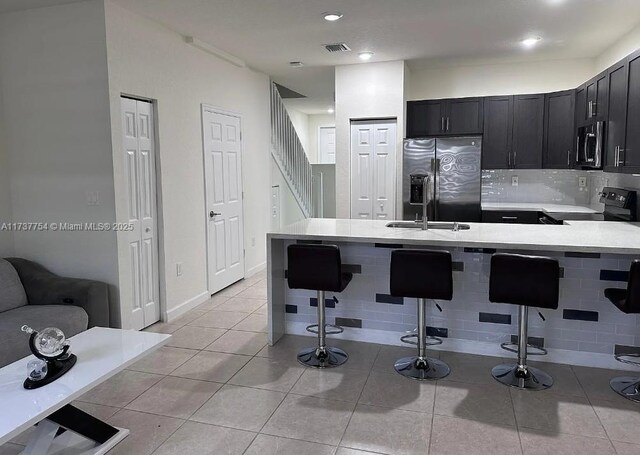 10519 W 33rd Ct Unit 10519, Hialeah, FL 33018 - kitchen with electric range, refrigerator with ice dispenser, a kitchen bar, light countertops, and dark cabinetry