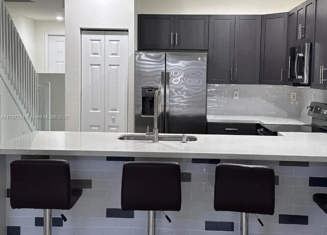 10519 W 33rd Ct Unit 10519, Hialeah, FL 33018 - kitchen featuring appliances with stainless steel finishes, a breakfast bar, backsplash, dark cabinets, and light stone countertops