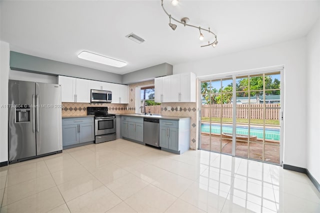 kitchen with white cabinets, stainless steel appliances, gray cabinets, and backsplash