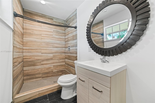 bathroom with vanity, toilet, and tiled shower