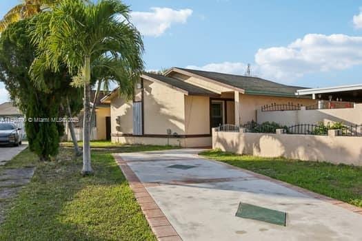 view of front of home with a fenced front yard, a front lawn, and stucco siding