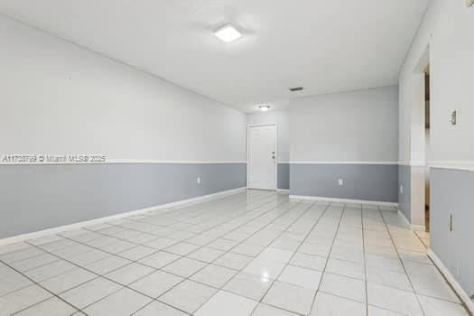 unfurnished room with light tile patterned floors and baseboards