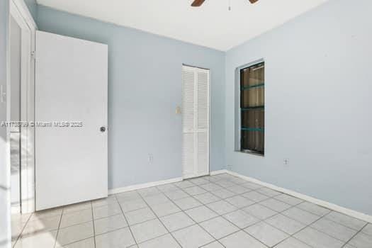 unfurnished room with ceiling fan, light tile patterned floors, and baseboards