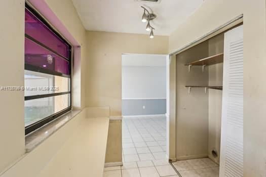 interior space with baseboards, track lighting, and light tile patterned floors