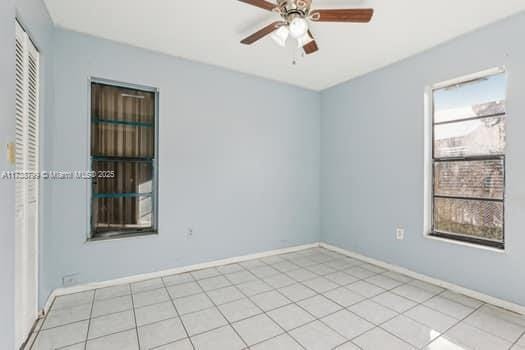 unfurnished room with a ceiling fan, light tile patterned flooring, and baseboards