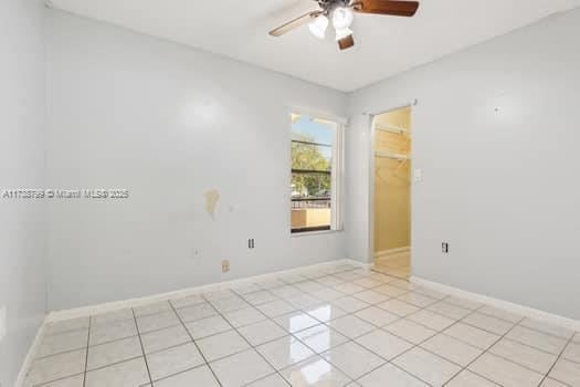 empty room featuring a ceiling fan, baseboards, and light tile patterned floors