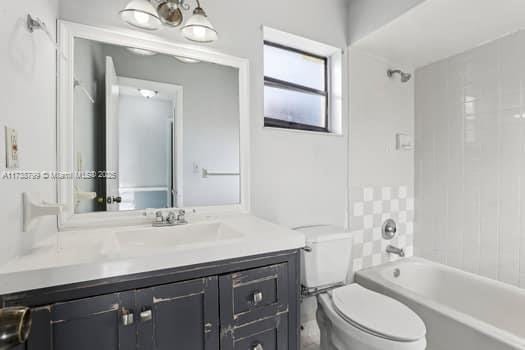 full bath featuring toilet, vanity, and bathing tub / shower combination