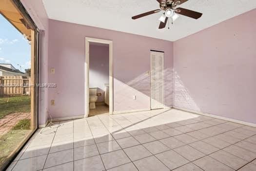 empty room with ceiling fan, baseboards, and light tile patterned floors