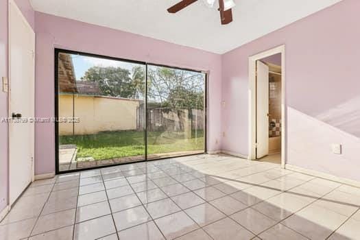 empty room with ceiling fan, light tile patterned flooring, and baseboards