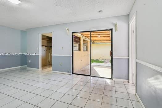 spare room featuring light tile patterned flooring, a textured ceiling, and baseboards