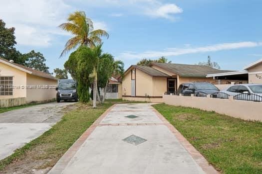 view of front of home featuring a front lawn, concrete driveway, and stucco siding