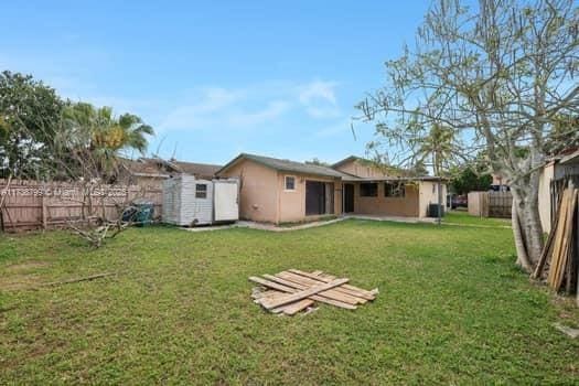 rear view of house with a storage shed, a fenced backyard, a yard, and an outdoor structure