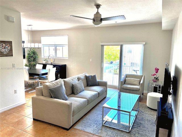 living room featuring ceiling fan, a healthy amount of sunlight, a textured ceiling, and light tile patterned floors