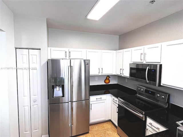 kitchen with light tile patterned flooring, appliances with stainless steel finishes, and white cabinets