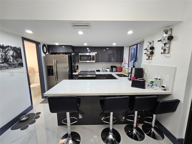 kitchen with sink, tasteful backsplash, a kitchen breakfast bar, kitchen peninsula, and stainless steel appliances