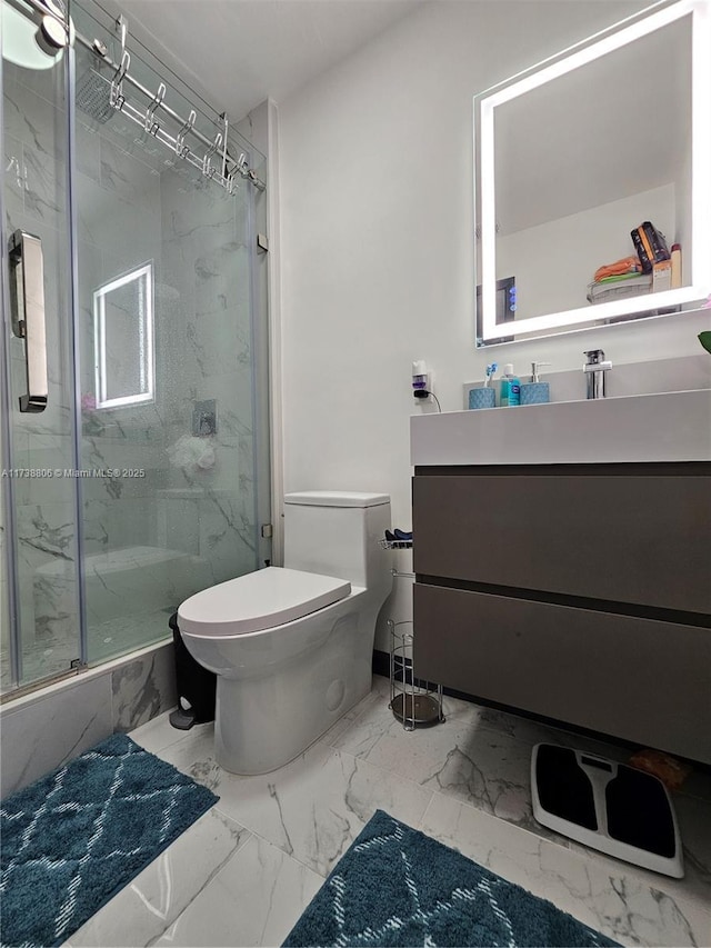 bathroom featuring vanity, a shower with shower door, and toilet