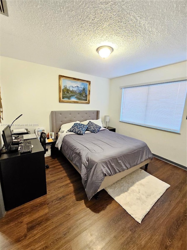 bedroom with dark wood-type flooring and a textured ceiling