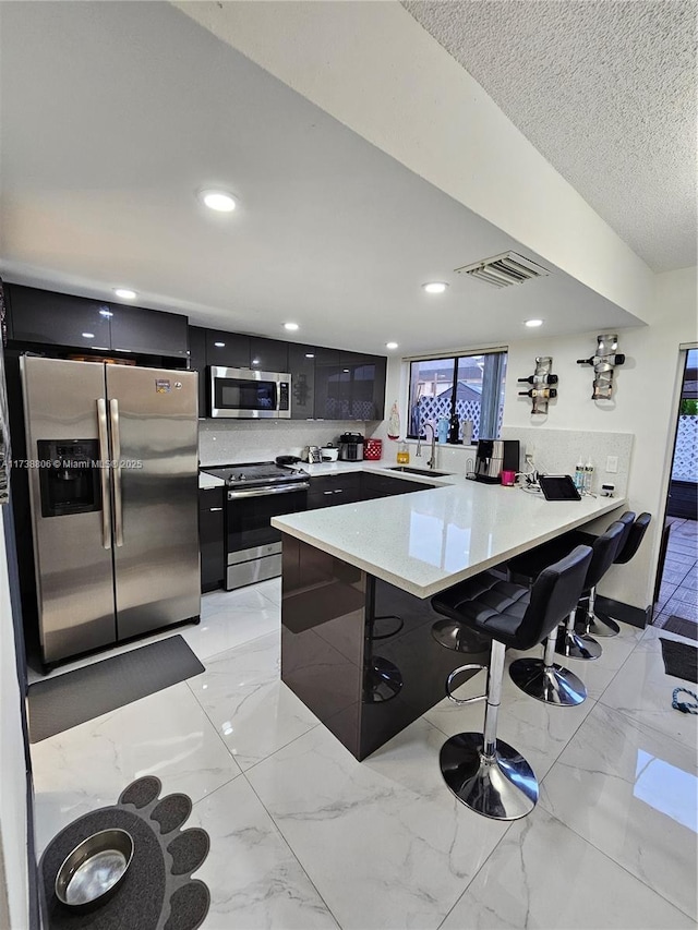 kitchen with tasteful backsplash, sink, a breakfast bar area, kitchen peninsula, and stainless steel appliances