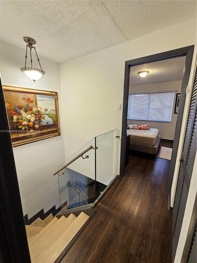 staircase with hardwood / wood-style flooring and a textured ceiling