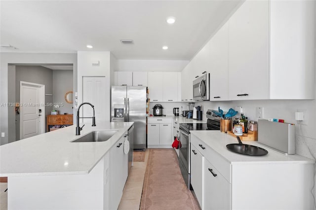 kitchen featuring sink, a center island with sink, light tile patterned floors, stainless steel appliances, and white cabinets