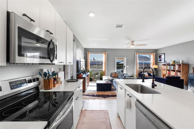 kitchen featuring light tile patterned flooring, sink, appliances with stainless steel finishes, ceiling fan, and white cabinets