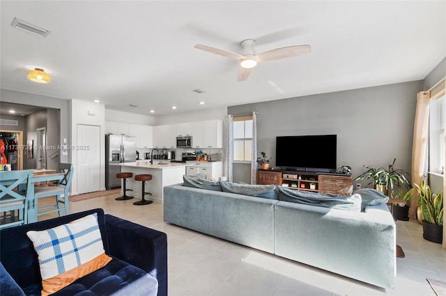 tiled living room with ceiling fan and sink