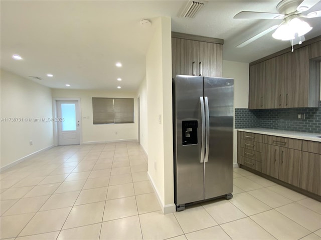 kitchen featuring stainless steel refrigerator with ice dispenser, ceiling fan, light tile patterned flooring, and tasteful backsplash