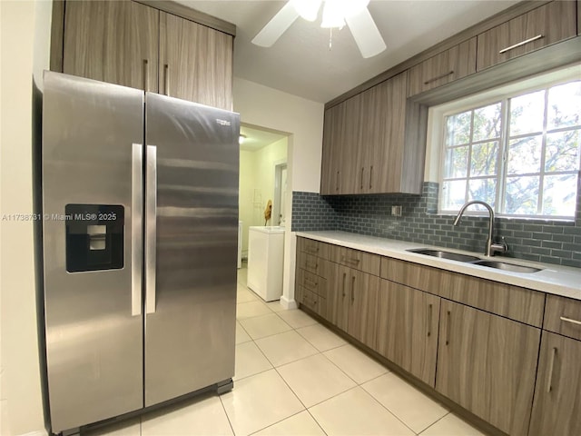 kitchen with sink, stainless steel fridge, tasteful backsplash, light tile patterned flooring, and separate washer and dryer