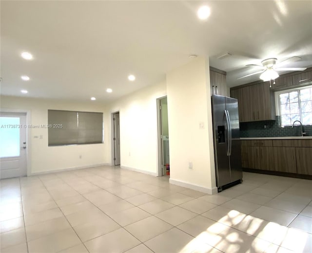 kitchen featuring light tile patterned floors, ceiling fan, dark brown cabinets, stainless steel fridge with ice dispenser, and decorative backsplash