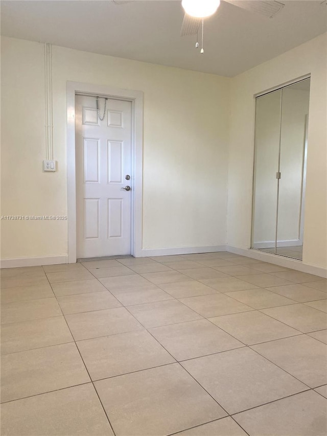 tiled spare room featuring ceiling fan