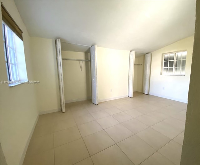 unfurnished bedroom featuring vaulted ceiling and multiple closets