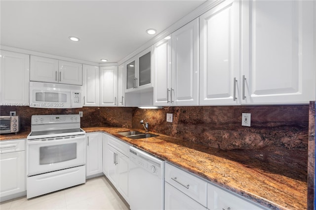 kitchen with white appliances, dark stone counters, sink, and white cabinets