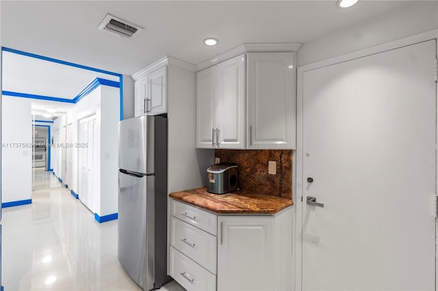 kitchen featuring white cabinetry, tasteful backsplash, and stainless steel refrigerator